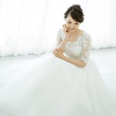 a woman in a white wedding dress sitting on the floor with her hand under her chin