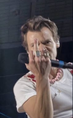 a woman holding a microphone up to her face and making the peace sign with her hand