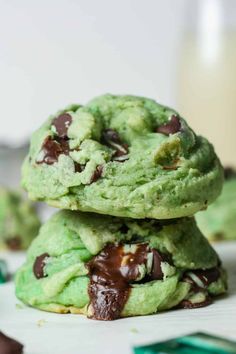 two cookies stacked on top of each other with chocolate chips and mints in the background