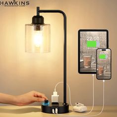 a hand is plugging an iphone charger into a lamp with two phones connected to it