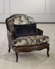 an old chair with floral upholstered fabric on the seat and back, sitting in front of a white paneled wall