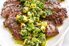 steak with broccoli and cucumber salad on a white serving platter