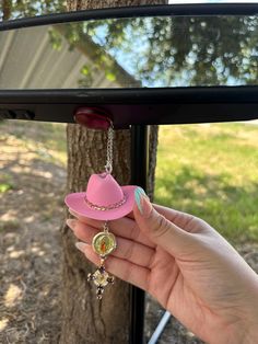 a woman's hand holding a pink hat and necklace