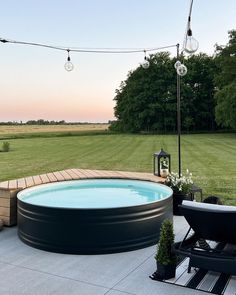 an outdoor hot tub in the middle of a yard with string lights hanging over it