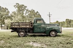 an old green truck parked in the grass