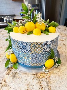 a blue and white decorated cake with lemons on the top sitting on a counter