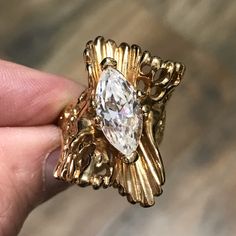 a gold ring with a large white diamond in it's center and leaves around the band