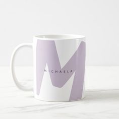 a coffee mug with the name michaela on it in pink and white colors, sitting on a marble surface