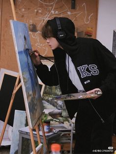 a young man is painting on an easel