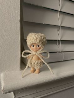 there is a small doll sitting on the window sill