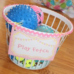 a basket filled with toys on top of a wooden table next to a bowl full of balls