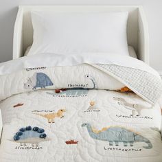 a bed with a quilted dinosaur pattern on it and the words pottery barn kids