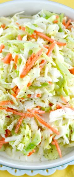 a bowl filled with coleslaw and carrots on top of a yellow table cloth