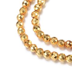 a gold beaded necklace on a white background