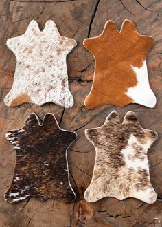 three different animal hide rugs sitting on top of a piece of wood