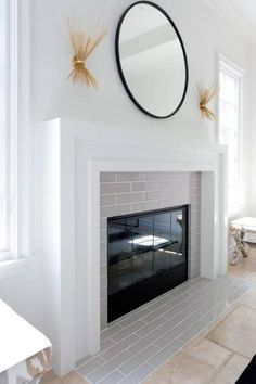 a white fireplace with a mirror above it