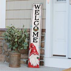 a welcome sign sitting next to a potted plant on the side of a house