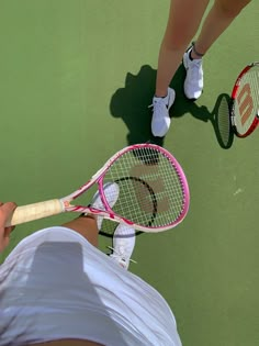 two people holding tennis racquets on a court