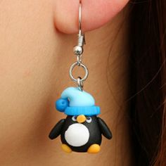 a close up of a pair of earrings with a penguin wearing a hat on it