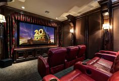 a home theater with red leather recliners in front of a large screen television