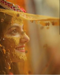 a woman with yellow powder on her face wearing a headdress and gold jewelry