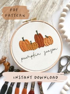 an embroidery kit with pumpkins on it next to some scissors and thread spools