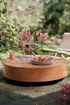 a wooden table with flowers on it in the middle of a garden area next to a bench