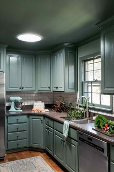 a kitchen with green painted cabinets and stainless steel appliances, including a dishwasher