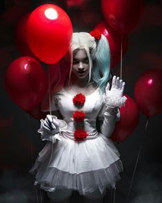 a woman dressed as a clown holding red balloons in her hands and wearing a white dress