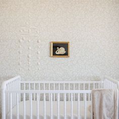 a baby's crib in front of a wall with a painting on it