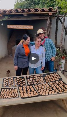 three people standing in front of a table with food on it