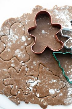 two cookie cutters sitting next to each other on top of snow covered ground with cookies in the shape of christmas trees