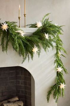 a fireplace decorated with christmas greenery and white starlight garland on the mantel