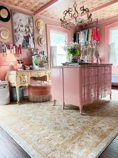 a room with pink furniture and pictures on the walls, including a chandelier