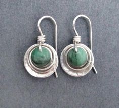 Raw genuine green emerald gemstones, weighing 1.8 carats each (3.6 carats/pair), are wrapped in sterling silver wire, then set within a sterling round dangle. Ear wires are also handcrafted in sterling silver wire. Artisan elegance and lightweight design make these earrings perfect for all day wear and comfort. Also are a great gift for a special someone with a May birthday, as emerald is May's birthstone. Raw genuine emeralds, 1.8 carats each (3.6 carats per pair), are opaque green with natural Unique Green Everyday Jewelry, Green Sterling Silver Wire Wrapped Jewelry, Nickel-free Green Jewelry In Sterling Silver, Nickel-free Green Sterling Silver Jewelry, Green Wire Wrapped Sterling Silver Jewelry, Wire Wrapped Green Sterling Silver Jewelry, Unique Green Sterling Silver Jewelry, Green Sterling Silver Dangle Jewelry, Handmade Green Sterling Silver Jewelry