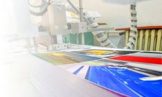 a large number of different colored papers on a table with a machine in the background