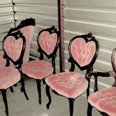 several pink chairs with hearts on them sitting in front of a white wall and a mirror