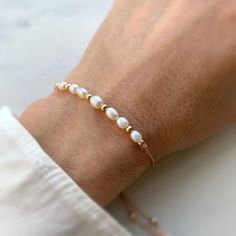 Delicate genuine freshwater pearl bracelet made with a blush pink thread and 14kt gold filled beads. The bracelet has a slider bead, which makes it easy to adjust the tightness to your liking. Individually selected high quality pearls make the bracelet truly special and one of a kind. The delicate and minimalist design goes well with both casual and sophisticated looks. You can layer the bracelet or wear it by itself. Total length of the bracelet: 13in Size of the freshwater pearl beads: 5-4mm S Adjustable White Pearl Bracelet In 14k Gold Filled, Dainty Adjustable Single Strand Pearl Bracelet, Adjustable Pearl Bracelet With Pearl Drop And Round Beads, Adjustable Pearl Drop Bracelet, Rose Gold Beaded Bracelets With Pearl Charm, Pearl White Adjustable Pearl Charm Bracelet, Adjustable Hand-strung Pearl White Pearl Bracelet, Elegant Adjustable 14k Gold-filled Beaded Bracelet, Adjustable Hand-strung White Pearl Bracelet