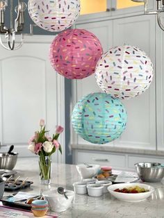 three paper lanterns hanging from the ceiling above a table with plates and bowls on it