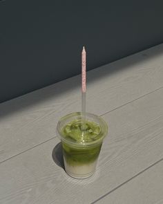 a plastic cup filled with green liquid and a pink stick sticking out of the top