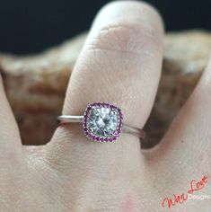 a woman's hand with a diamond and pink sapphire ring on top of her finger