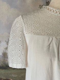 A charming historically inspired blouse that can be used in outfits ranging from the Edwardian era to the 1960's! This piece features a dainty eyelet lace yoke, scalloped lace mock-neck collar, short sleeves, and a gathered bodice. A versatile choice for building your historical wardrobe. This piece is part of our sustainable Secondhand, Vintage, and Upcycled Collection, and thus stock is limited to one! Sizing: Tag size XL, Fits like an XL.Bust up to 44 Inches / 110 CentimetersWaist up to 44 Inches / 110 CentimetersLength - 24.5 / 62 CentimetersSleeve Length - 8 / 22 CentimetersSleeve Width - 8 Inches / 22 Centimeters Condition: B | Some feeling of use, no major flaws. Materials: 100% Polyester synthetic "linen." The Edwardian Era, Fantasy Shop, Gathered Bodice, Eyelet Blouse, Medieval Fashion, Edwardian Fashion, Edwardian Era, Curated Vintage, Baroque Fashion