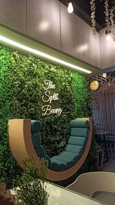 an indoor seating area with green plants on the wall and chairs in front of it