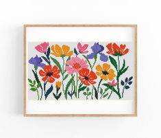 a cross stitch pattern with colorful flowers on the front and back, in a wooden frame