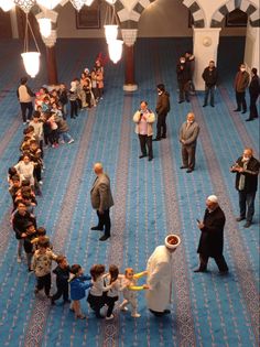 a group of people standing around each other in a room with blue carpet and chandeliers