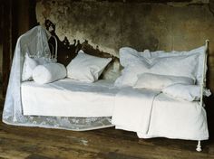 an old bed with white sheets and pillows