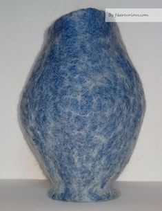 a blue vase sitting on top of a white table next to a wall and floor