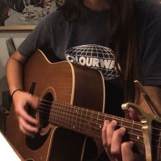 a woman is playing an acoustic guitar in her living room