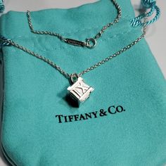 Tiffany & Co. Atlas Cube Roman Numerals Necklace Pendant. Discontinued Tiffany Necklace 16" Long, Comes With Tiffany & Co. Pouch Displayed In Pictures . Formal Silver Jewelry With Logo Charm, Formal Silver Necklace With Logo Charm, Formal White Gold Necklace With Logo Charm, Elegant Silver Necklace With Logo Charm, Silver Jewelry With Logo Charm For Anniversary, Anniversary Silver Jewelry With Logo Charm, Elegant Tan Necklace For Gift, Elegant Tan Necklaces For Gifts, Classic Formal Jewelry With Logo Charm