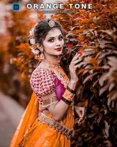 a woman dressed in an orange and pink outfit holding a red flower with her right hand